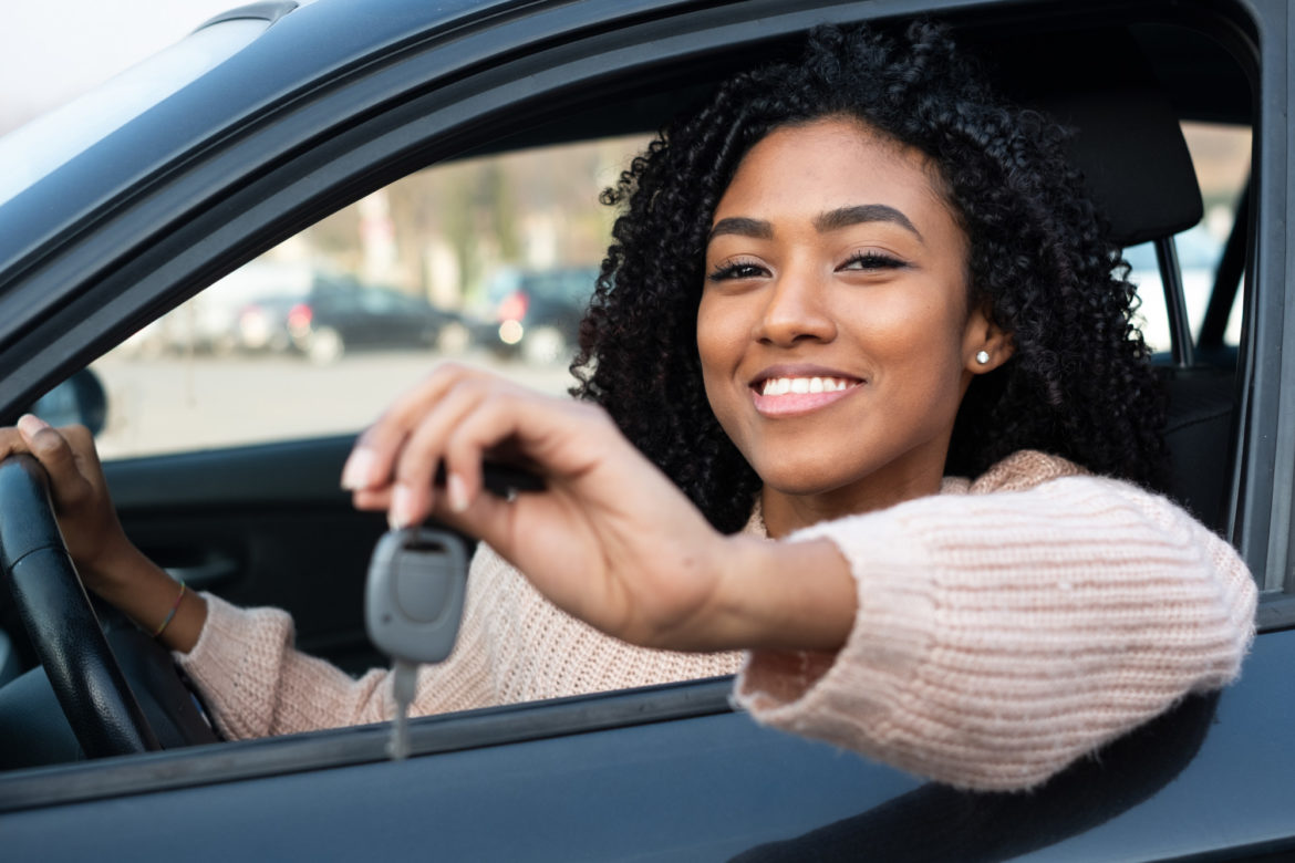 Happy young woman learning to drive car